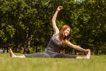Pretty redhead smiling stretching in park