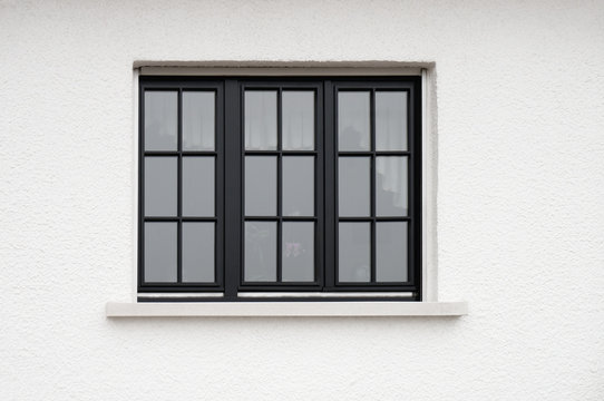 Dunkles Holzfenster in wei&szlig;er Fassade mit Rauputz