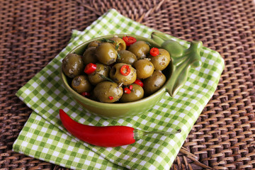 Green olives in oil with spices and rosemary in bowl