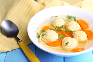 Soup with meatballs and noodles in bowl on wooden background