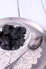 Metal tray with glass bowl of prunes, lace doily and spoon
