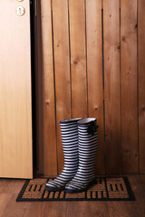 Fototapeta premium Dirty wellington boots on door mat in room