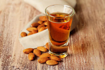 Dessert liqueur Amaretto with almond nuts, on wooden table