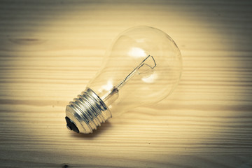 Light bulb on wooden table. Retro style. Photo toned yellow