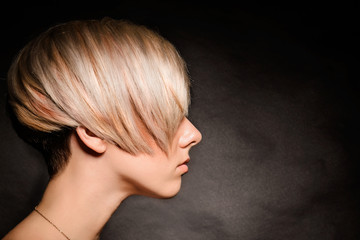 Blonde girl with a short stylish haircut on a dark background