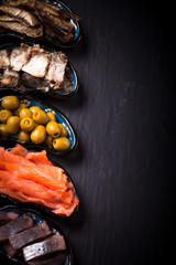 Fish assortment and olives on a plate on a dark background. With