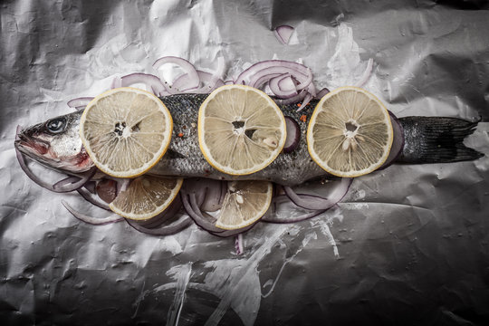 Fish prepared for roasting on the foil with lemon and onion