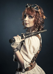 Beautiful redhair steampunk girl with gun looking at camera