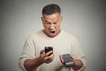 Man looking on phone calculator disgusted with financial bills
