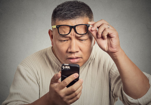 man with glasses having trouble seeing phone screen