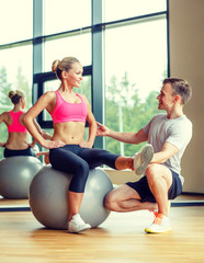 Obraz premium smiling man and woman with exercise ball in gym