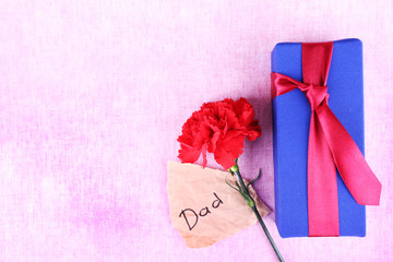 Happy Father's Day with gift box, red carnation and piece of