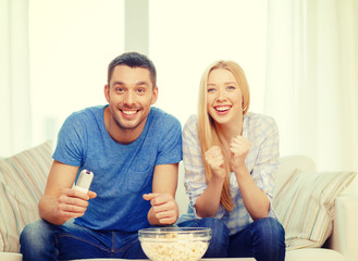 smiling couple with popcorn cheering sports team