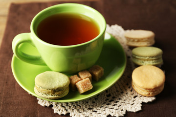 Obraz na płótnie Canvas Cup of tea with colorful macarons on wooden background
