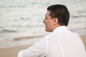 Fototapeta na wymiar ragazzo seduto sulla sabbia guarda il mare