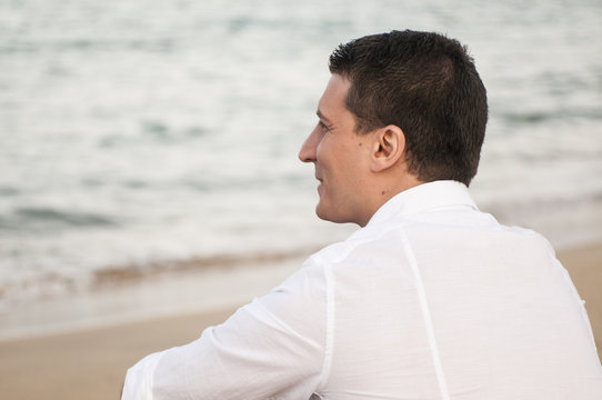 ragazzo seduto sulla sabbia guarda il mare