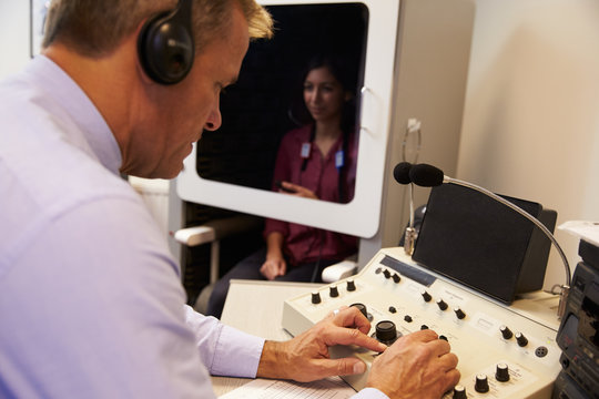 Audiologist Carrying Out Hearing Test On Female Patient