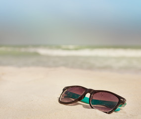 Fototapeta na wymiar Sunglasses in the sand on the seashore. vacation time