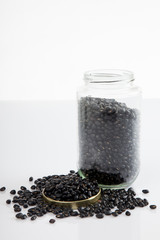 Fototapeta na wymiar Black beans in a jar on white table with lid off
