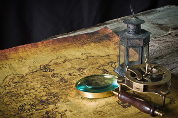 Magnifier with lantern with compass on the old map