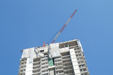 Crane and building construction site against blue sky