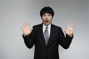 흰 배경 스튜디오에서 검은 정장을 입고 미소를 지으며 제스처를 취하는 젊은 남성 