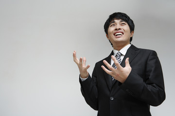 흰 배경 스튜디오에서 검은 정장을 입고 미소를 지으며 제스처를 취하는 젊은 남성 