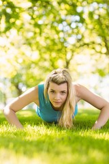 Fit blonde doing push ups in the park