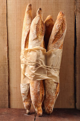 French baguettes in paper on wooden background