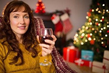 Woman sitting on a couch while holding a glass of red wine