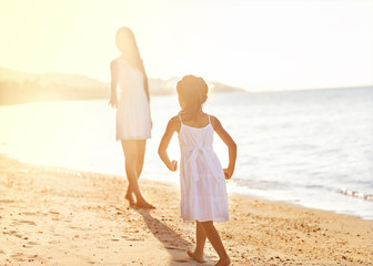 Mother and daughter happily running along the beach, Thailand