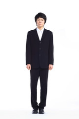 Obraz na płótnie Canvas 스튜디오 안에서 검은 정장을 입고 서있는 젊은 비즈니스맨