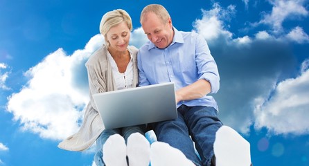 Composite image of happy mature couple using laptop