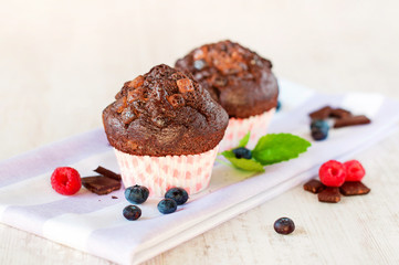 Two delicious chocolate muffins with pieces of chocolate and ber
