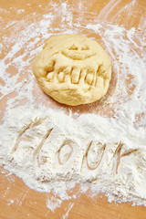 Funny knead dough and flour on wooden table with text