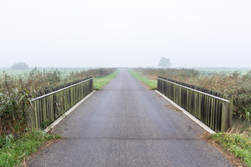Bridge over water in a misty morning rural landscape in the Neth