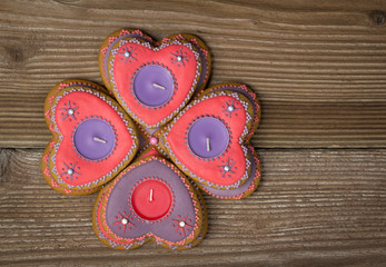 Gingerbread hearts with candles on wooden background