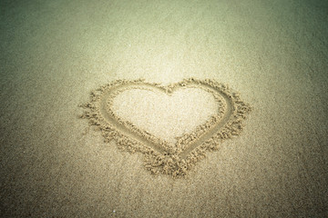 Heart drawn in the sand. Beach background. Tinted