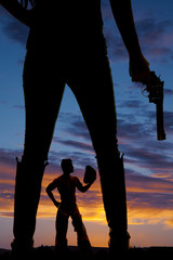 silhouette of a woman legs in boots holding gun cowboy between l