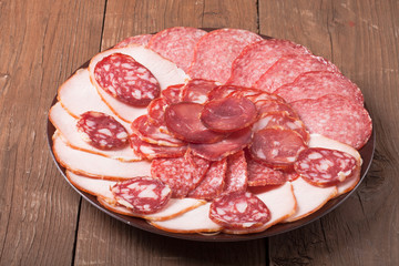 plate with different sliced sausage on an old wooden table. Tint