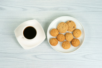 Coffee cup with oatmeal cookies on the white plate