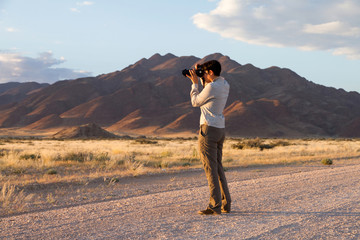 Young woman is photographing the Sossusvlei park, Namibia