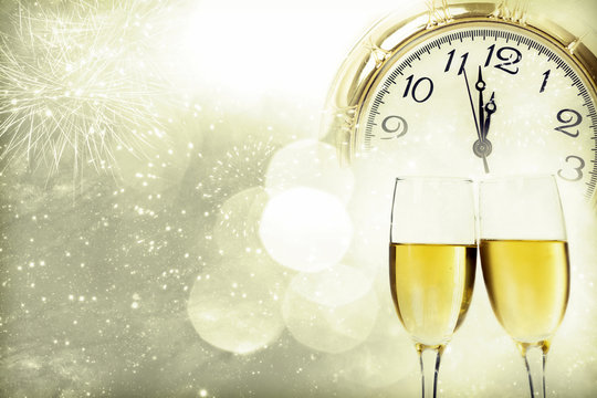 Champagne against fireworks, clock close to midnight and sparkli