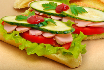 Big appetizing fast food baguette sandwich with lettuce, tomato
