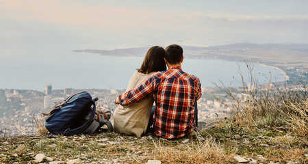 Couple in love sitting on hill and looking at the city