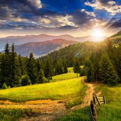 fence on hillside meadow in mountain at sunset - obrazy, fototapety, plakaty
