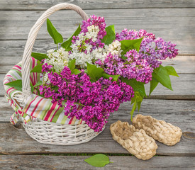 White basket with lilacs and bast shoes