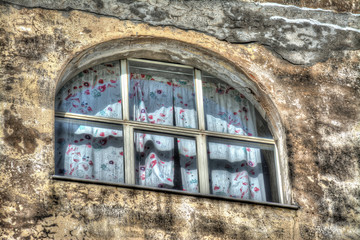 old window with curtain in a rustic wall