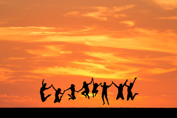 silhouetted friends jumping in sunset
