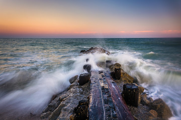 Fototapeta premium Waves and a jetty at sunset in the Atlantic Ocean at Edisto Beac